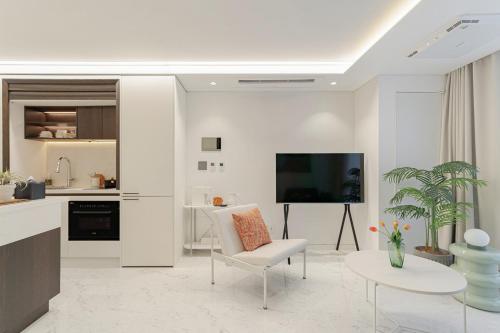 a white living room with a tv and a white chair at Le Collective Gangnam SAC Roium in Seoul
