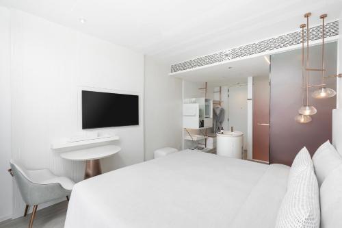 a bedroom with a white bed and a sink and a mirror at INNSiDE by Meliá Bangkok Sukhumvit in Bangkok