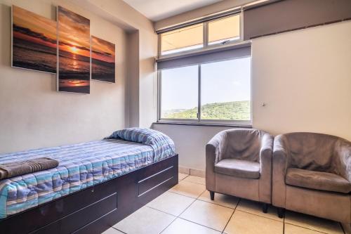 a bedroom with two chairs and a bed and a window at ATKV Natalia in Kingsburgh