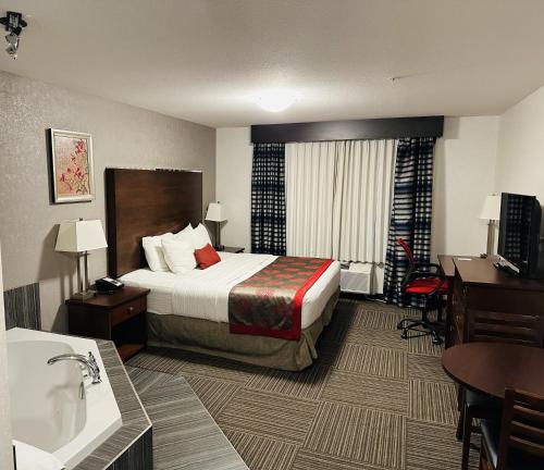 a hotel room with a bed and a bathroom at Ramada by Wyndham Moose Jaw in Moose Jaw