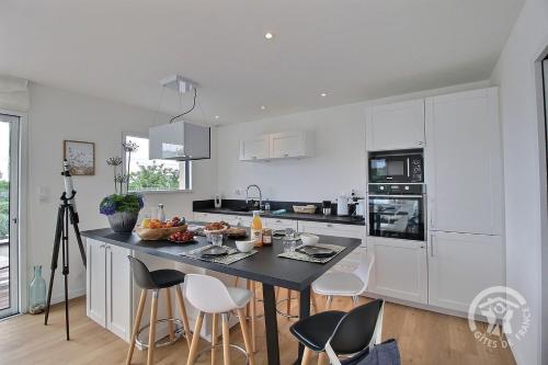 une cuisine blanche avec un îlot au milieu dans l'établissement Le menhir, à Pleumeur-Bodou