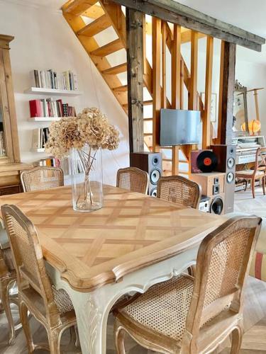 - une table à manger avec des chaises et un vase fleuri dans l'établissement Maison bucolique champs de blé, à Villers-Agron-Aiguizy