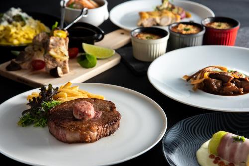a table full of plates of food with meat and french fries at Rihga Royal Hotel Kokura Fukuoka in Kitakyushu