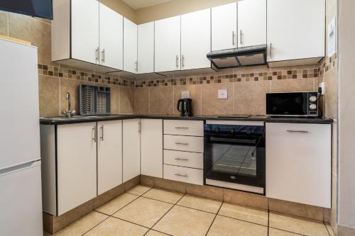 a kitchen with white cabinets and a microwave at ATKV Natalia in Kingsburgh