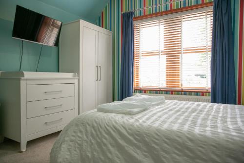 a bedroom with a bed and a dresser and a window at Modern Family Home - Gateway to Yorkshire in Leeds