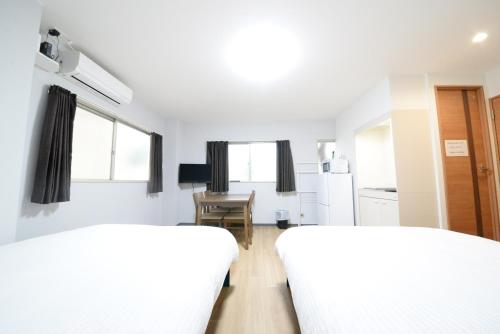 two beds in a white room with a desk at 和の楓cottage第二202 新宿歌舞伎町近隣 in Tokyo