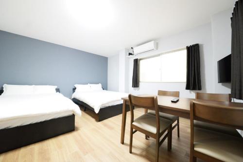 a room with two beds and a table and a desk at 和の楓cottage第二202 新宿歌舞伎町近隣 in Tokyo
