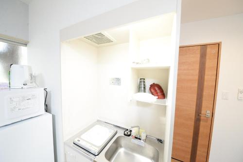 a small kitchen with a sink and a refrigerator at 和の楓cottage第二202 新宿歌舞伎町近隣 in Tokyo