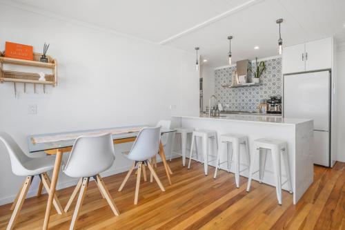 a kitchen with a white counter and white stools at The Olive Corner- Martinborough Holiday Home in Martinborough 