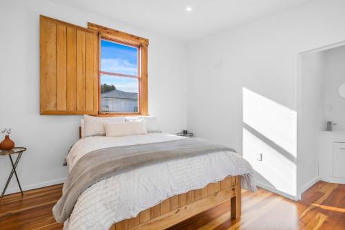 a white bedroom with a bed and a window at The Olive Corner- Martinborough Holiday Home in Martinborough 