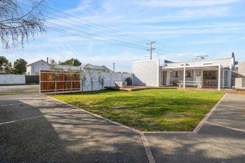 a house with a grassy yard next to a street at The Olive Corner- Martinborough Holiday Home in Martinborough 