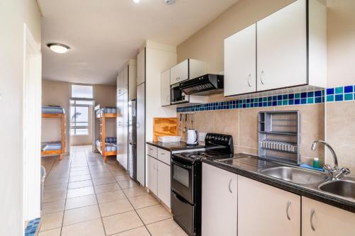 a kitchen with white cabinets and black appliances at ATKV Natalia in Kingsburgh
