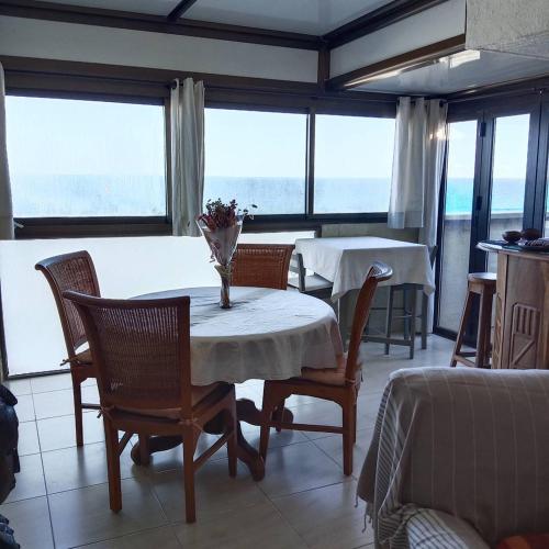 - une salle à manger avec 2 tables, des chaises et des fenêtres dans l'établissement Appartement T2 face Mer, moderne, clim, parking 4NOUM6, à Canet