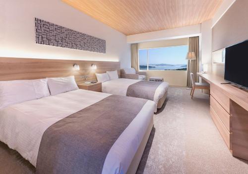 a hotel room with two beds and a flat screen tv at Setouchi Kojima Hotel Kurashiki in Kurashiki
