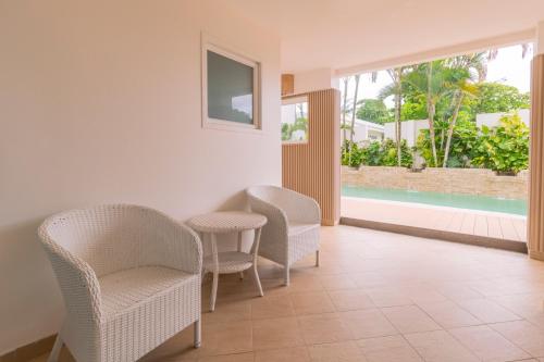 a living room with chairs and a table and a pool at Hotel Santa Teresa by the Beach in Santa Teresa Beach