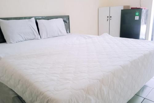ein großes weißes Bett mit weißer Bettwäsche und Kissen in der Unterkunft RedLiving Apartemen kemang View - My Room LapanLapan Tower Mahagoni in Pekayon Satu
