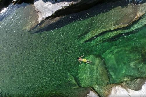 a person swimming in a body of water at Wild Valley Private Paradise in Valle Onsernone in Crana