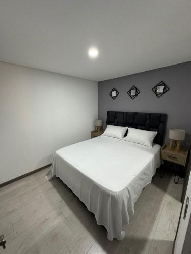 ein Schlafzimmer mit einem weißen Bett mit einem schwarzen Kopfteil in der Unterkunft DEPA EN SONATA 3 habitaciones in Santa Clara Ocoyucan