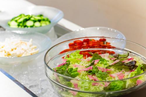 a salad in a bowl on a table with other bowls of food at Hotel Lifort Sapporo in Sapporo