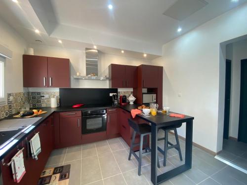 une cuisine avec des placards bruns et une table noire dans l'établissement Calme et volupté avec animaux, à Saint-Jean-Lasseille