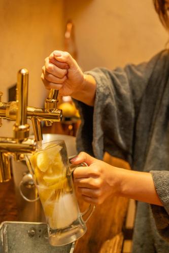 a woman is making a drink in a glass at farm and bed SETODA in Onomichi