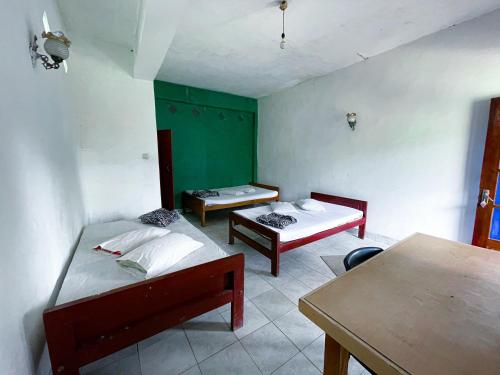 a room with two beds and a table in it at New Uduwara Guest in Ella