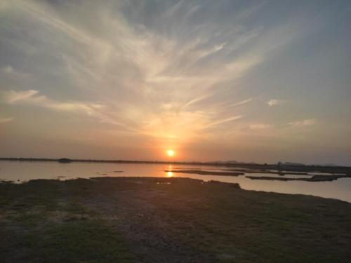 a sunset over a body of water with the sun setting at Hotel Bijay Niwas Palace in Bijainagar