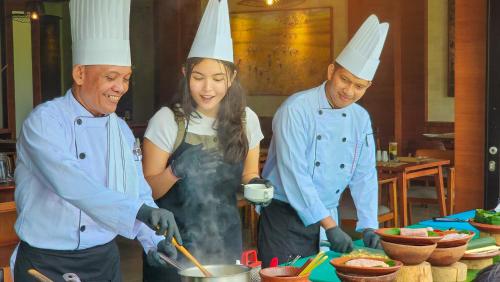 a group of three chefs preparing food in a kitchen at tanadewa Resort Ubud Bali by Cross Collection in Ubud