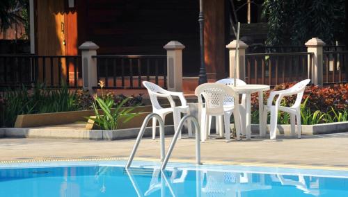 a table and chairs next to a swimming pool at Maeyom Palace Hotel in Phrae