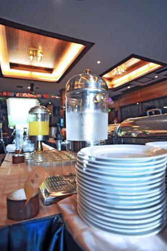 a stack of plates on a counter in a restaurant at Maeyom Palace Hotel in Phrae