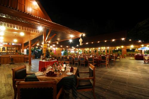 a restaurant with tables and chairs and lights at Maeyom Palace Hotel in Phrae