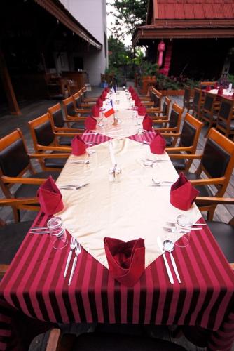 a long table with red napkins and forks and knives at Maeyom Palace Hotel in Phrae