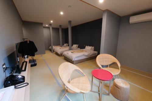 a room with a bed and two chairs and a table at Kusatsu Onsen Kusatsu Hotel1913 in Kusatsu