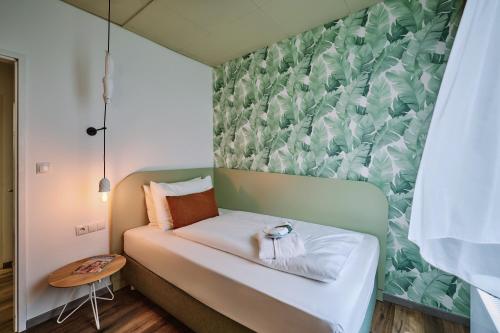 a small bed in a room with a green and white wallpaper at The Weekend Hotel in Vienna