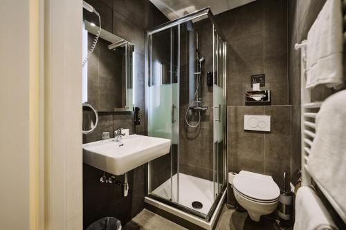a bathroom with a sink and a shower and a toilet at The Weekend Hotel in Vienna