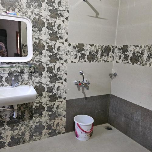 a bathroom with a sink and a mirror and a bucket at Bridge Point Home Stay in Kushālnagar