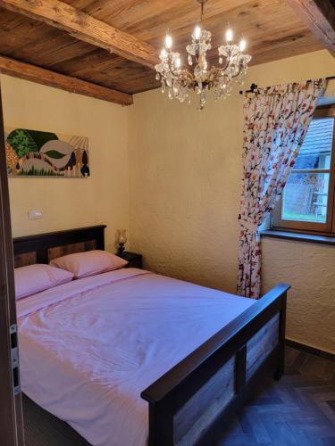 a bedroom with a large bed and a chandelier at Rose garden in Ljubno