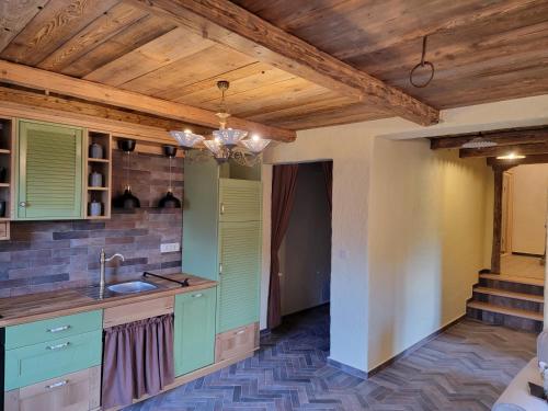 a kitchen with green cabinets and a wooden ceiling at Rose garden in Ljubno