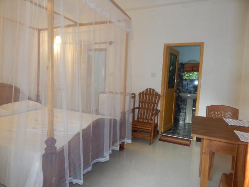 a bedroom with a canopy bed and a wooden desk at Little Angels in Mirissa