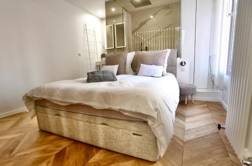 une chambre avec un grand lit avec des draps blancs dans l'établissement Appartement cosy CANNES, à Cannes