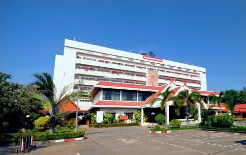 a large white building with a parking lot in front of it at Maeyom Palace Hotel in Phrae