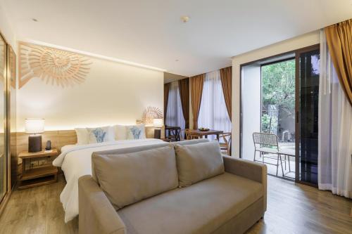 a hotel room with a bed and a couch at The Marin Phuket Kamala Beach in Kamala Beach