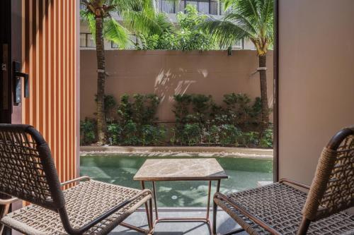 a patio with two chairs and a table and a pool at The Marin Phuket Kamala Beach in Kamala Beach