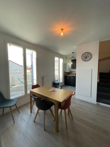 - un salon avec une table, des chaises et une horloge dans l'établissement T2 duplex au calme proche commodités, à Vaujours