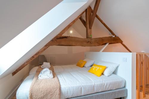a bed with yellow and white pillows in a attic at La Petite Maison du Pêcheur - Proche plage pour 5p in Sarzeau