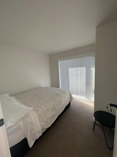 a white bedroom with a bed and a window at Beauty by the beach in Papamoa
