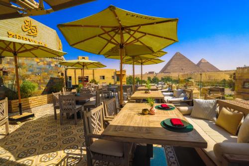 a restaurant with tables and chairs with pyramids in the background at Onyx Pyramids Boutique Hotel in Cairo