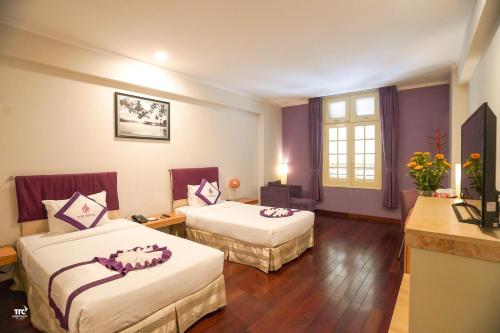 a hotel room with two beds with purple walls at TTC Hotel - Ngoc Lan in Da Lat