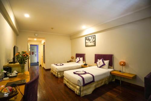 a hotel room with two beds and a desk at TTC Hotel - Ngoc Lan in Da Lat