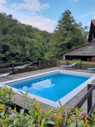 une grande piscine avec une terrasse en bois à côté dans l'établissement Gîte du barrage, à Châteauponsac